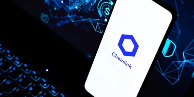 Smartphone apoyado sobre el teclado de un portátil y en la pantalla del móvil aparece el logo oficial de Chainlink.