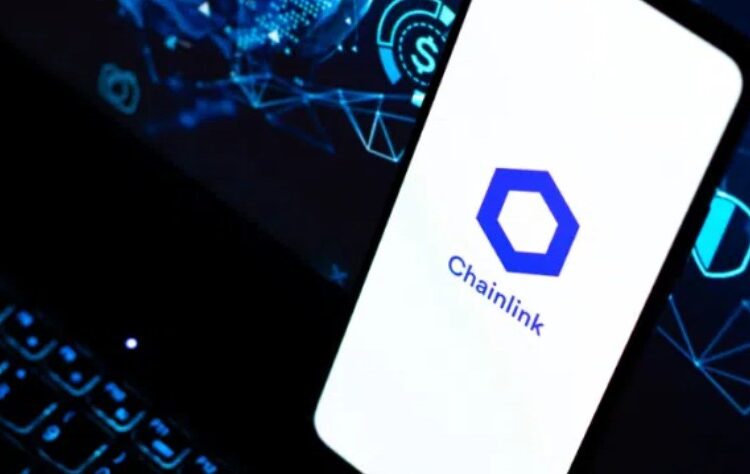 Smartphone apoyado sobre el teclado de un portátil y en la pantalla del móvil aparece el logo oficial de Chainlink.
