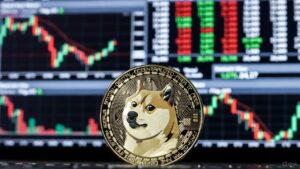 Moneda física de dogecoin en primer plano, al fondo un panel electrónico típico de Wall Street lleno de gráficos de velas rojas y verdes.