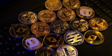 Monedas físicas doradas representativas de criptomonedas están sobre un teclado.