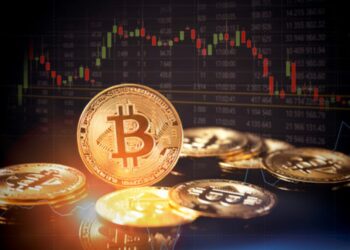 Moneda física de bitcoin con gráficas de precio atrás.