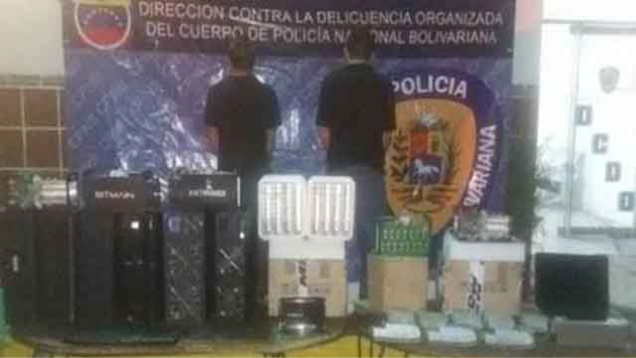 Dos personas de espalda con pendón de la policia bolivariana y mineros de bitcoin.