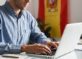 Una persona aparece junto con una laptop como declarando impuestos, al fondo se ve una bandera de España