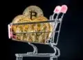Carrito de supermercado con varias monedas que tienen el logo de Bitcoin.