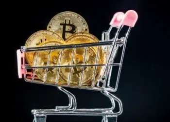 Carrito de supermercado con varias monedas que tienen el logo de Bitcoin.
