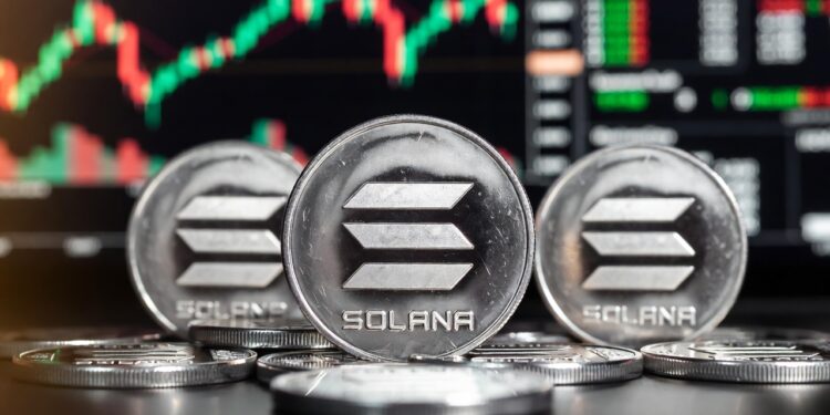 Varias monedas físicas de solana de acabado metálico con un fondo de gráficos de velas bursátiles.