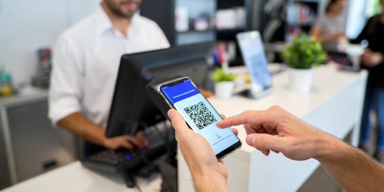 Una persona pagando con QR a través de su celular en un negocio.