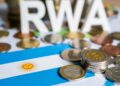 Monedas físicas representativas de bitcoin y otras monedas junto a una bandera de Argentina.