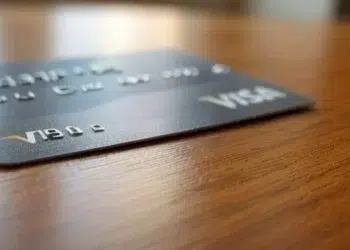 Tarjeta física VISA de color gris sobre una mesa.