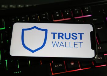 Un celular que muestra "Trust Wallet" en la pantalla apoyado sobre un teclado.