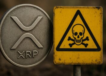 Moneda física de XRP al lado de un letrero de peligro de muerte de color amarillo.