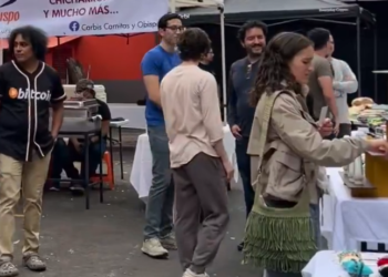 Una persona con una camiseta en la que se lee la palabra bitcoin camina en un mercado bitcoiner en México.