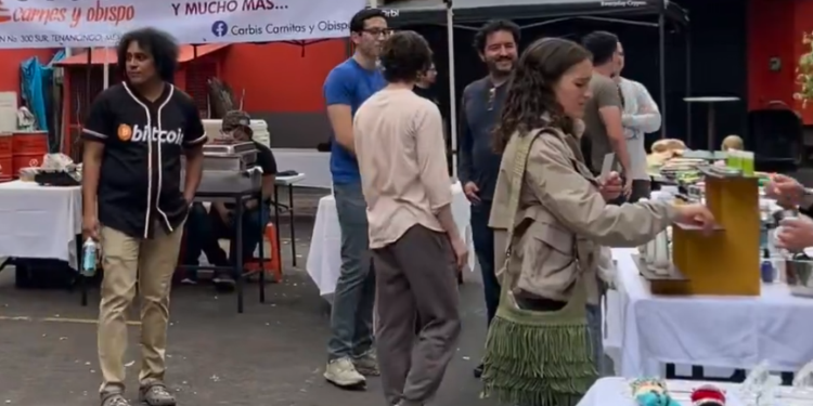 Una persona con una camiseta en la que se lee la palabra bitcoin camina en un mercado bitcoiner en México.