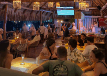 Un grupo de personas sentadas conversando en mesas dispersas por un lugar de Bitcoin Beach en El Salvador.