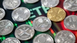 Varias monedas físicas de XRP dispersas y un gráfico bursátil en tonos verdes y rojos.