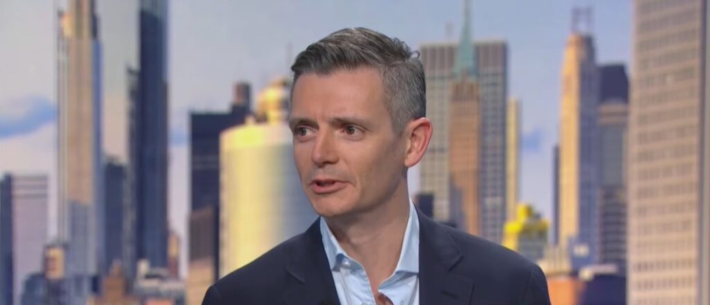 Jean-Marie Mognetti, director ejecutivo de CoinShares, vestido con traje oscuro y camisa celeste sin corbata en un estudio de televisión.