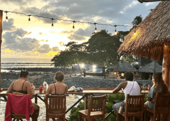 Un grupo de personas sentadas cenando frente a la playa en Bitcoin Beach de El Salvador.
