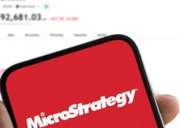 Un móvil con el logo de Microstrategy y en el fondo el precio de bitcoin.