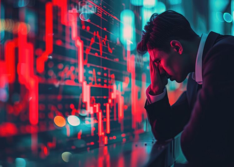 Inversionista con rostro preocupado, delante de un gráfico en rojo.