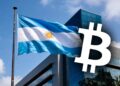 Bandera de Argentina junto a logo de bitcoin frente a un edificio.