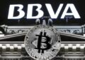Logo del BBVA junto a un logo de BTC, arriba de un edificio.