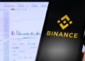 Mano sujetando un teléfono inteligente que muestra el logo de Binance.