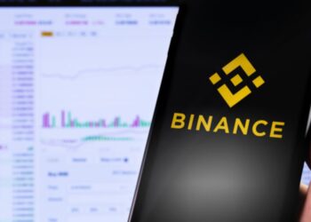 Mano sujetando un teléfono inteligente que muestra el logo de Binance.