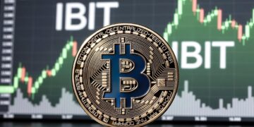 Una moneda física de bitcoin dorada y Al fondoaparece una pantalla de trading con un gráfico alcista en tonos verdes.