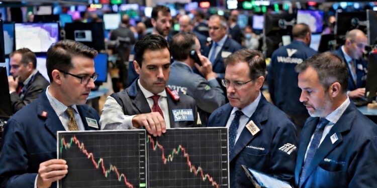 Cuatro brokers de Wall Street aparecen con gráficos a la baja en el medio de la bolsa de valores.