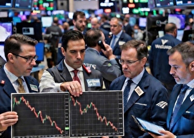 Cuatro brokers de Wall Street aparecen con gráficos a la baja en el medio de la bolsa de valores.