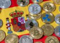 Muchas criptomonedas y detrás la bandera de España