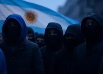 Encapuchados frente a una bandera de Argentina.