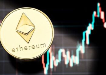 Moneda física de Ethereum dorada sobre gráficos de mercado.