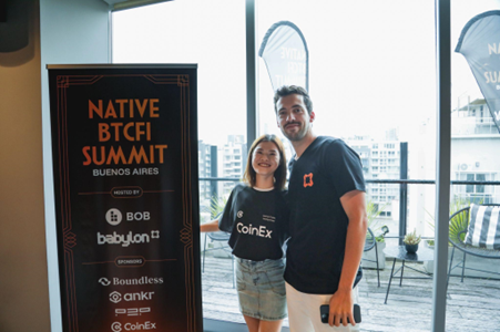 Un hombre y una mujer con vestidos camisas negras parados al lado de un cartel de Native BTCFi Summit.