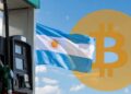 Bandera de Argentina junto a una estación de gasolina y un logo de bitcoin.