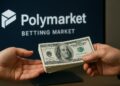 Manos de una persona entregando un fajo de billetes a otra y al fondo una pantalla con el logo de Polymarket.