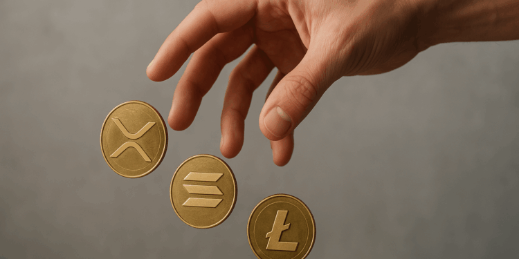 Mano humana vista en primer plano dejando caer tres monedas físicas doradas que representan los ETF de XRP, solana y litecoin.