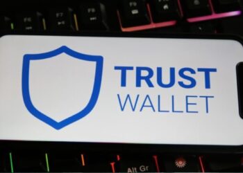 Un celular que muestra "Trust Wallet" en la pantalla apoyado sobre un teclado.