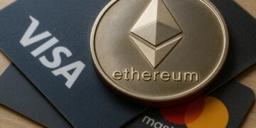 Moneda física de Ethereum plateada sobre dos tarjetas, una de Visa y otra de Mastercard.
