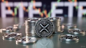 Monedas fรญsicas de XRP y al fondo, desenfocado, aparece un grรกfico de precios.