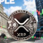 Moneda fรญsica de XRP en primer plano e imรกgenes tรญpicas de Wall Street en el fondo.