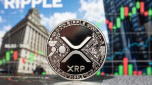 Moneda fรญsica de XRP en primer plano e imรกgenes tรญpicas de Wall Street en el fondo.