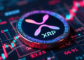 Una moneda física de XRP sobre gráficos de precio.