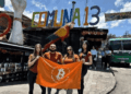 Personas con una bandera naranja de Bitcoin debajo de un que dice Comuna 13 en Medellรญn Colombia.