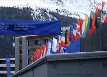 Banderas de varios países del mundo junto a un letrero que dice Annual Meeting Davos 2026 y de fondo los Alpes Suizos.