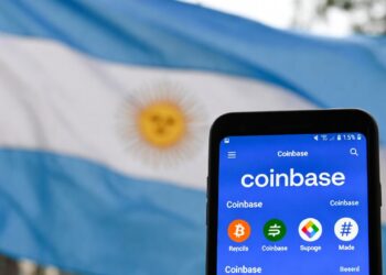 bandera de Argentina detrás de un smartphone con la interfaz de Coinbase.