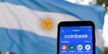 bandera de Argentina detrás de un smartphone con la interfaz de Coinbase.