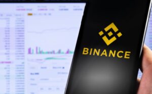 Mano sujetando un teléfono inteligente que muestra el logo de Binance.