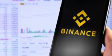 Mano sujetando un teléfono inteligente que muestra el logo de Binance.