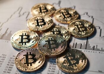 Unas monedas físicas de bitcoin sobre un gráfico de precios.